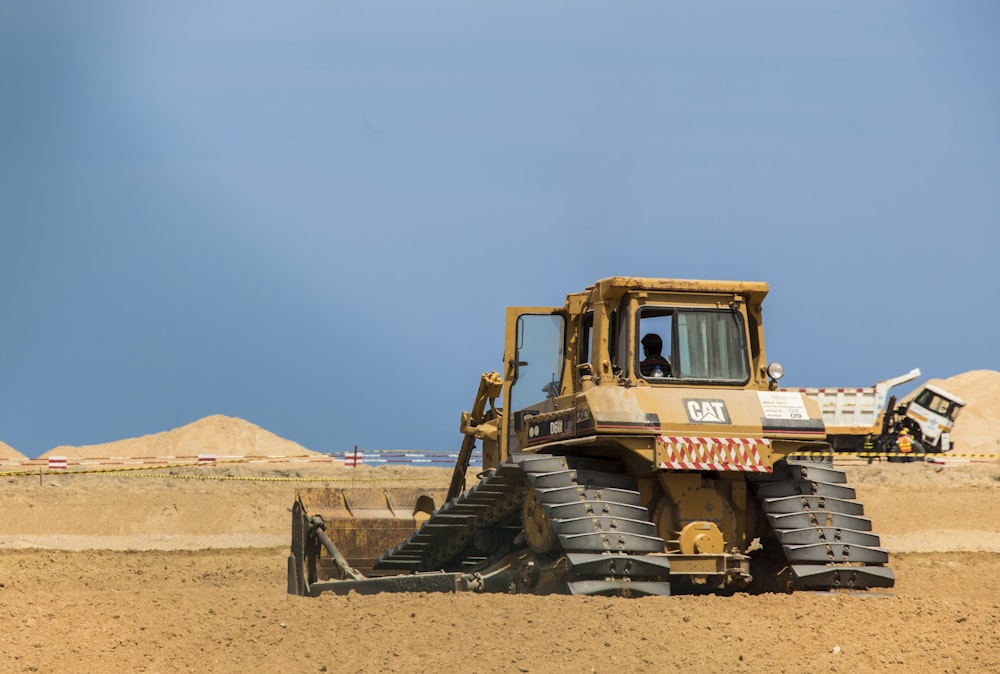 red and black tractor on brown sand during daytime