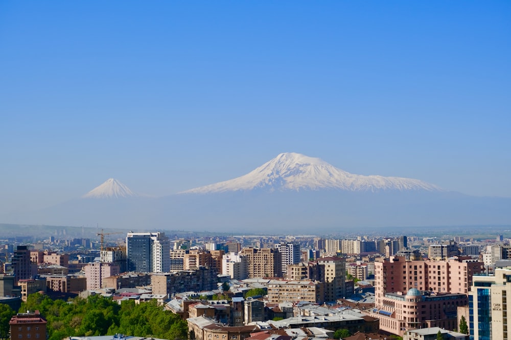 city skyline near snow covered mountain during daytime