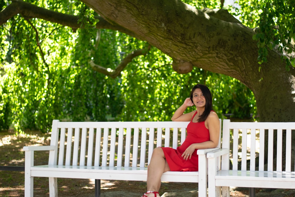 woman in red tank top sitting on brown wooden bench under tree