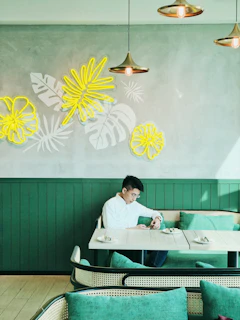 A relaxed man sitting in a modern café, wearing a crisp white shirt from the collection.