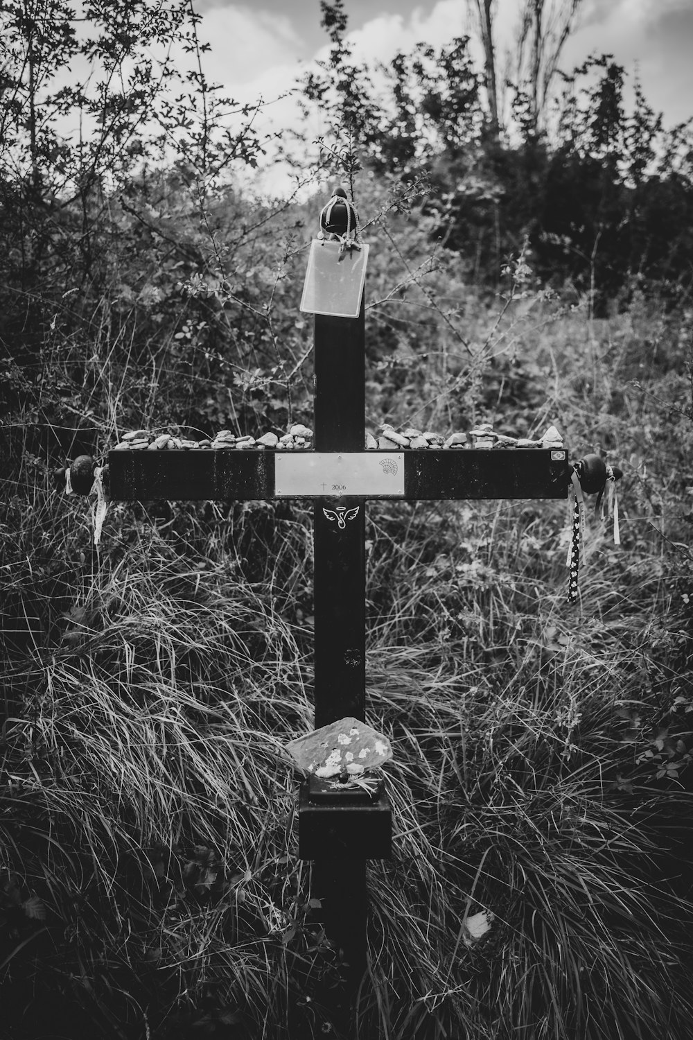 grayscale photo of cross in the middle of the forest