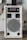 A white audio amplifier with a prominent speaker on the front, featuring a metal grille with a circular design. Above the speaker are red control knobs for various audio settings such as mic volume, echo, bass, treble, and balance. The device is rectangular and placed on a flat surface with several acoustic panels behind it.