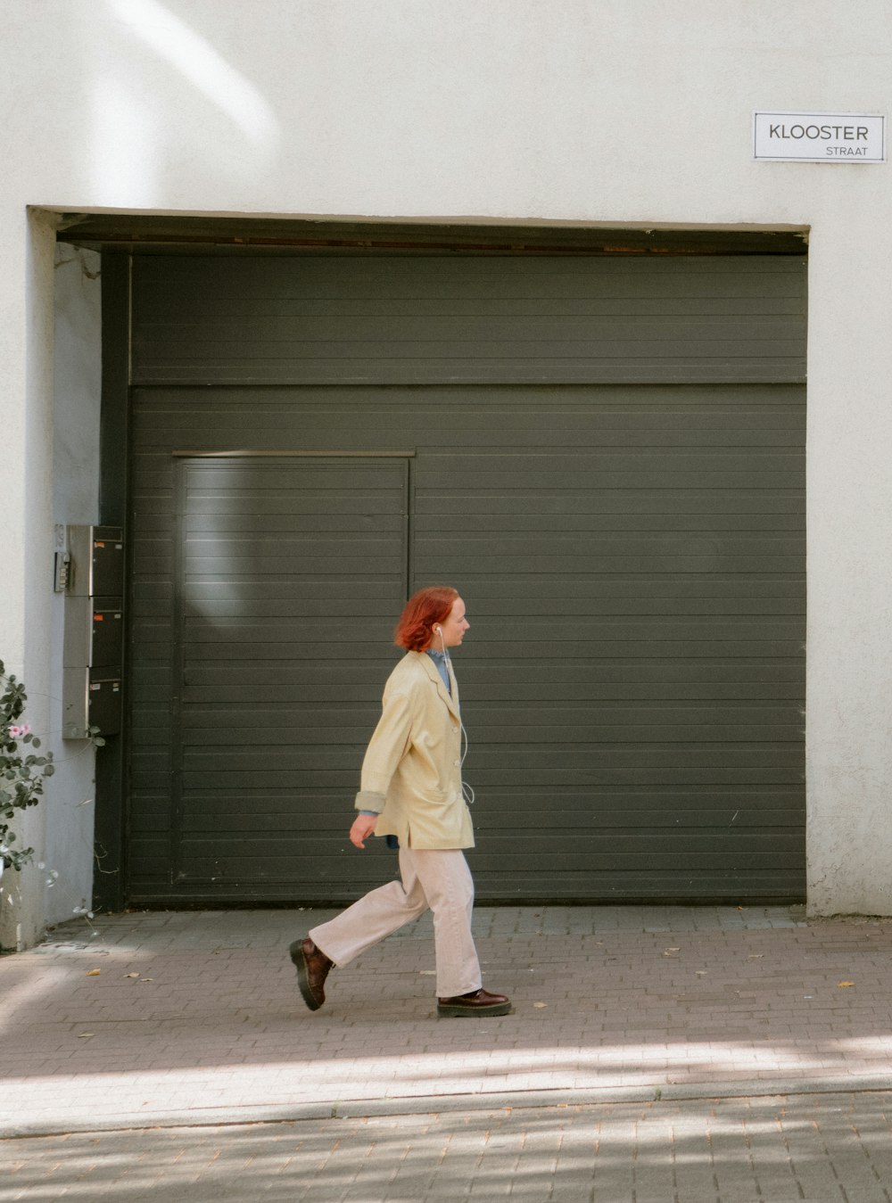 woman in white coat walking on sidewalk during daytime