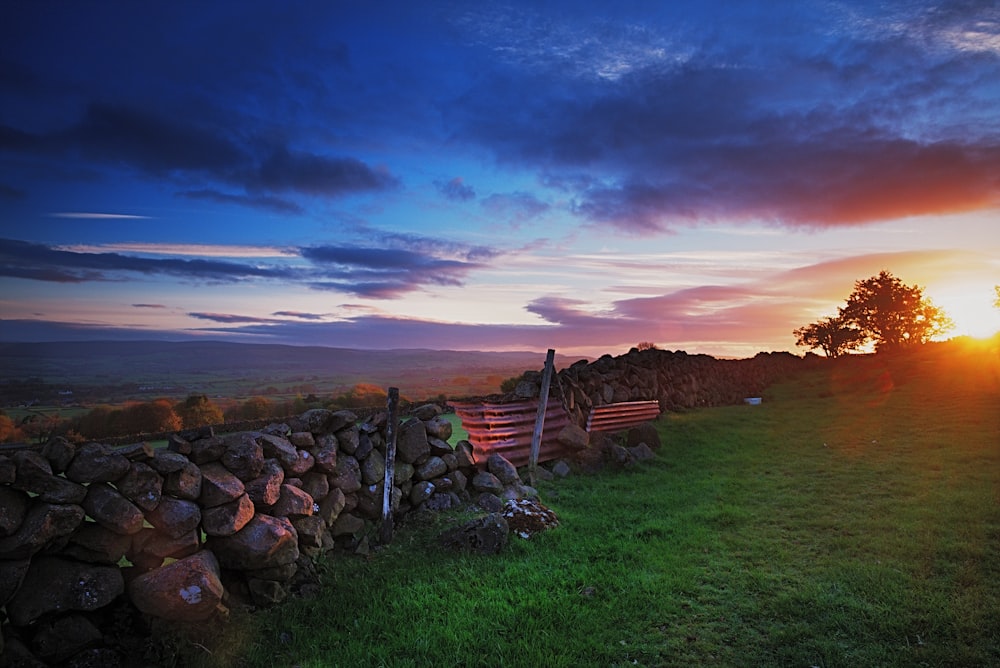 brown wooden fence on green grass field under cloudy sky during daytime