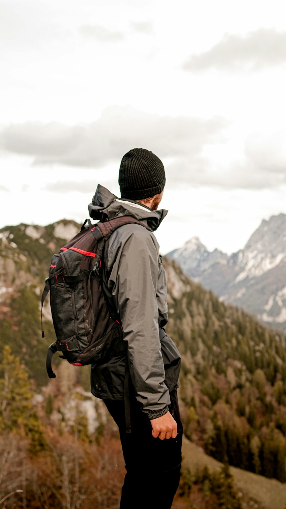 man in black knit cap and black jacket standing on mountain during daytime