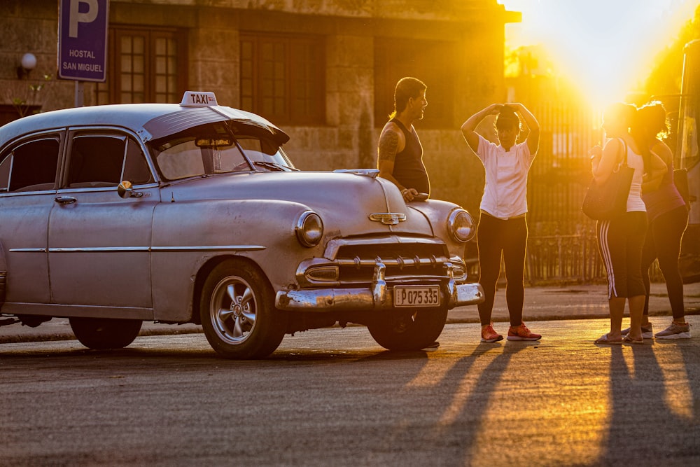 man in white t-shirt and white shorts standing beside white classic car during daytime