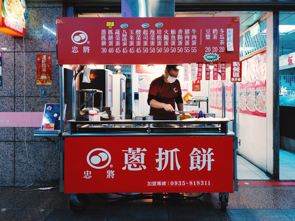 man in red shirt standing in front of counter