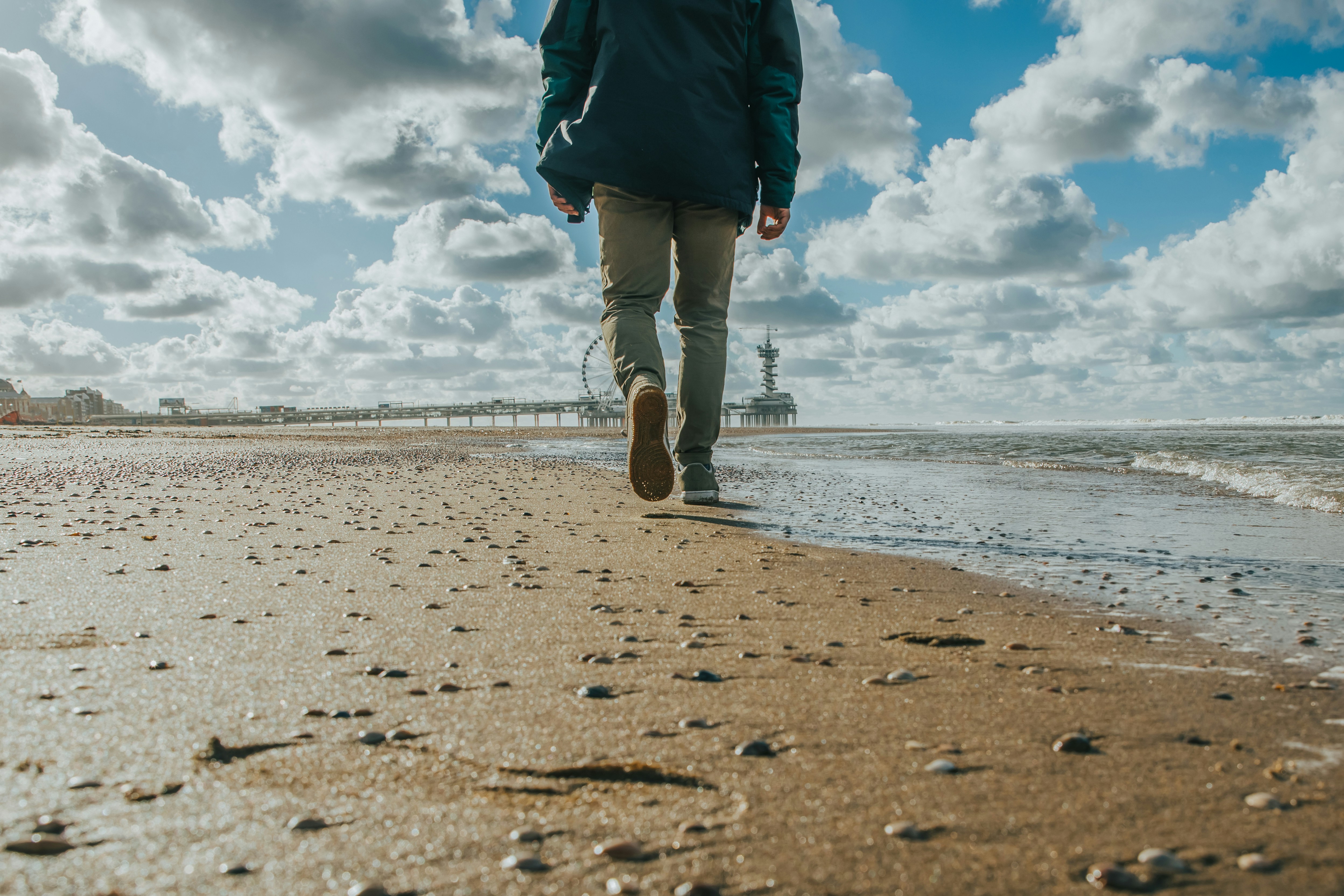 person in black jacket and brown pants standing on beach during daytime