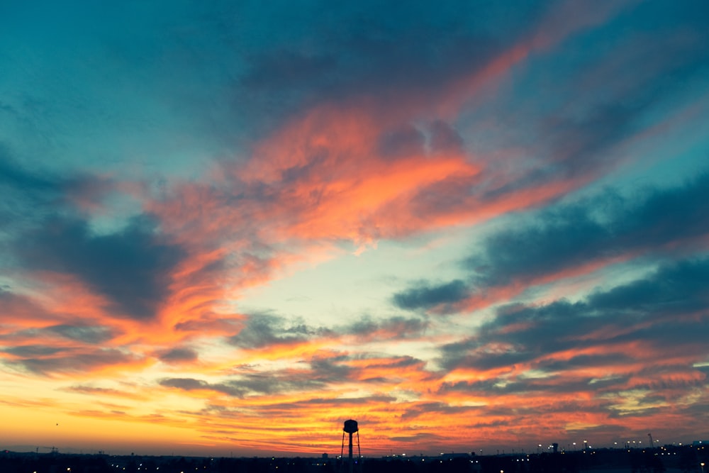 silhouette of person standing on seashore during sunset