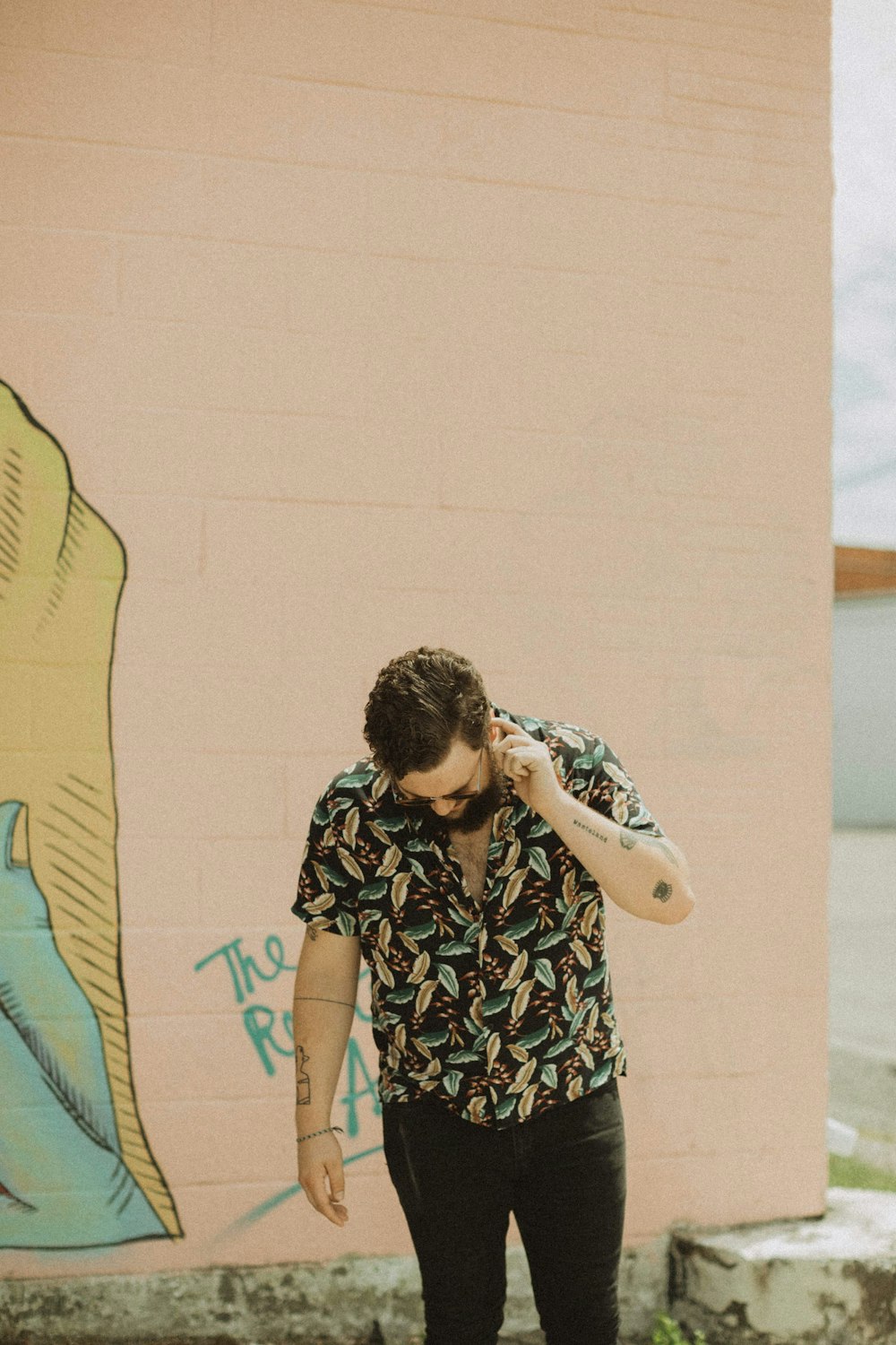 man in black and white floral shirt standing beside yellow and blue textile