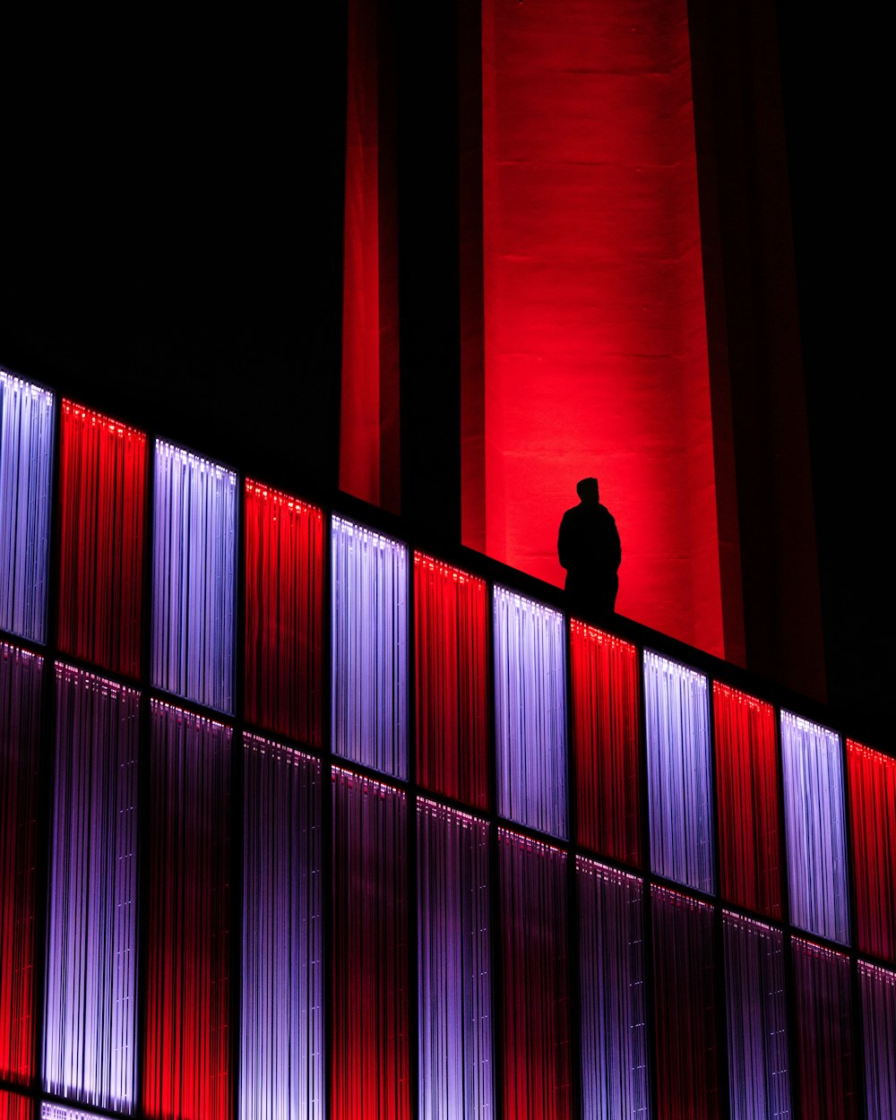 silhueta do homem de pé na parede listrada vermelha e preta