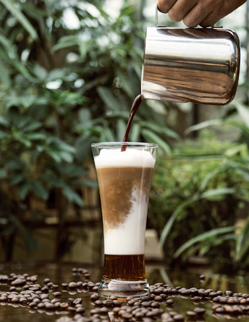 Close-up of creamy soy milk pouring into a glass with soft green and earthy background.