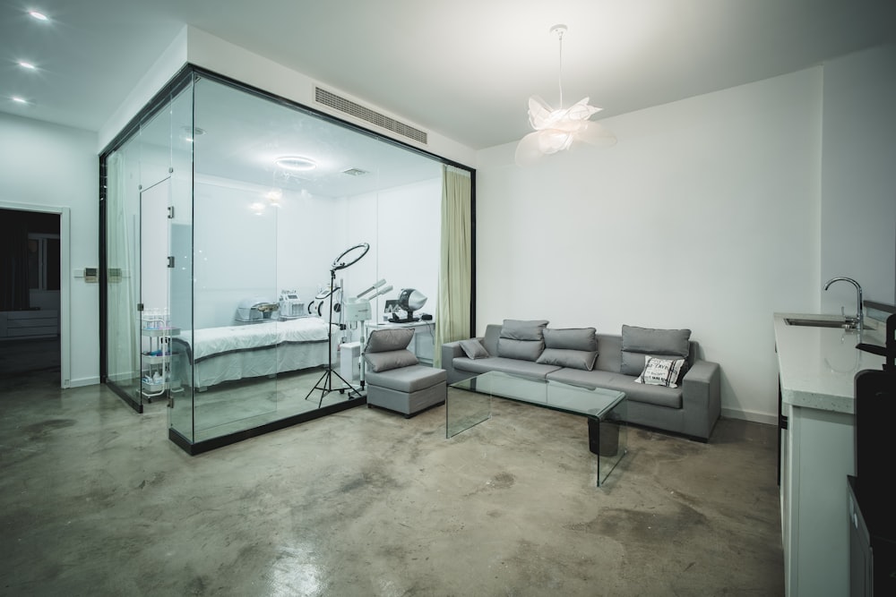 gray sectional couch beside glass top coffee table