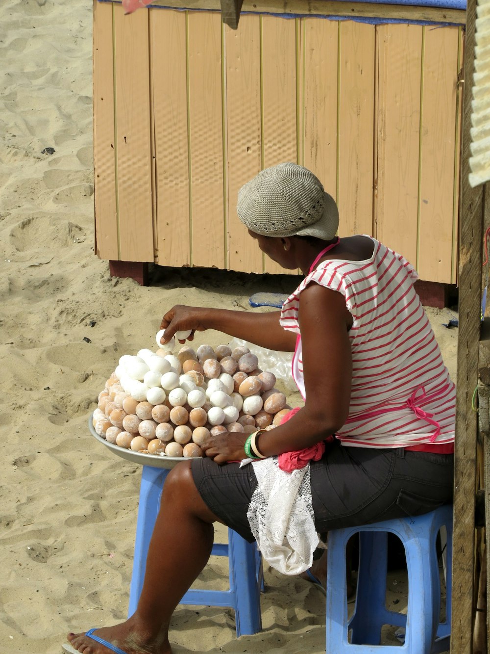 person in red and white stripe shirt holding brown eggs