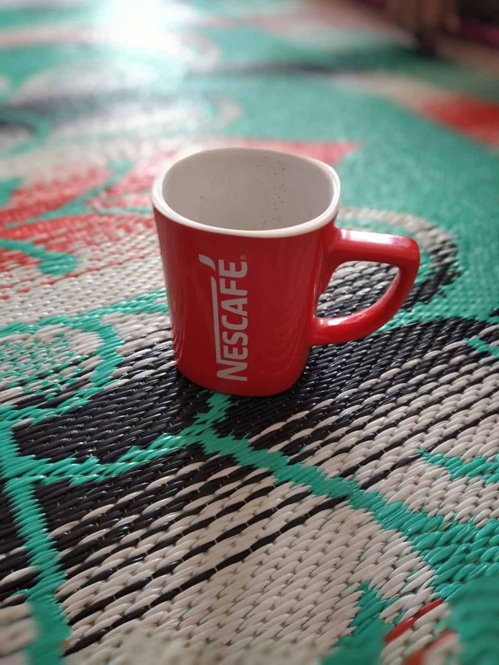 a red coffee cup sitting on top of a rug