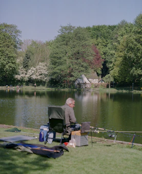 Coarse angler seated beside a UK stillwater reservoir with feeder rod