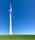 A large wind turbine stands prominently against a clear blue sky, situated on a lush green field. Its blades are positioned to capture wind energy efficiently.