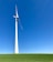 A large wind turbine stands prominently against a clear blue sky, situated on a lush green field. Its blades are positioned to capture wind energy efficiently.