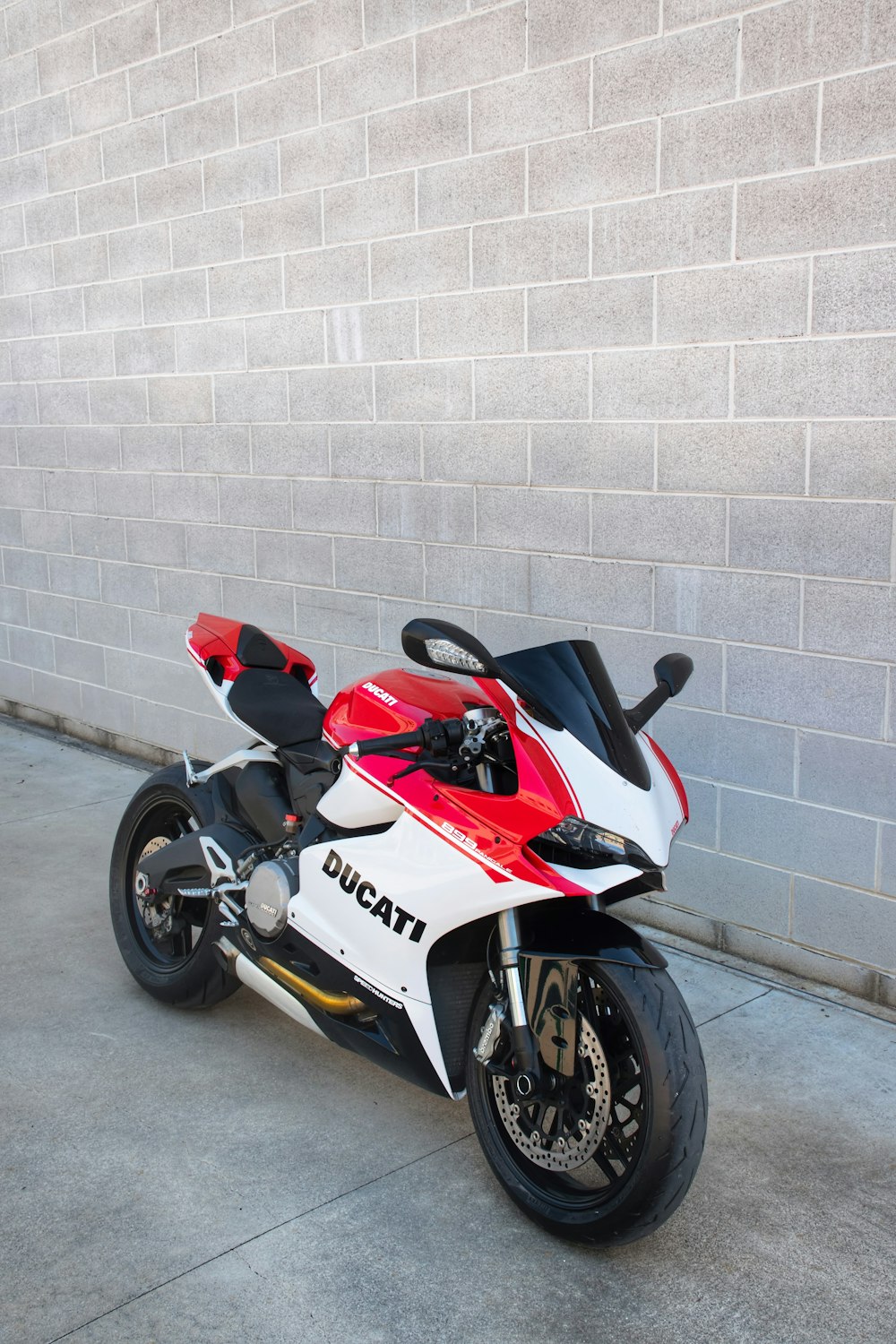 白い壁の脇に停められた赤と白のホンダスポーツバイク