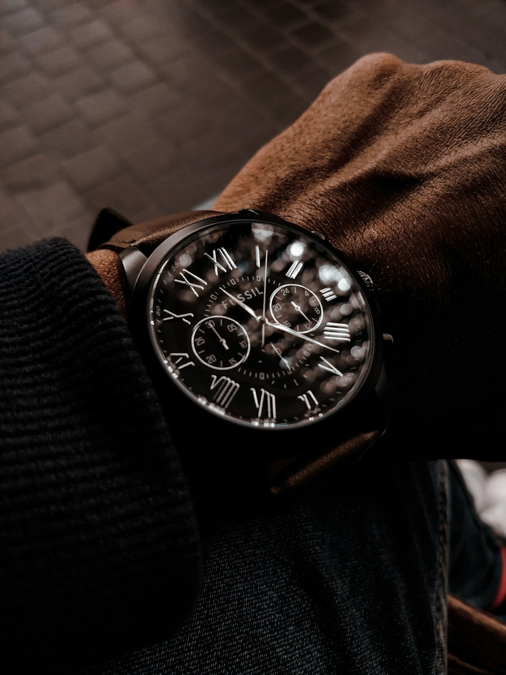 person wearing black leather strap silver round chronograph watch