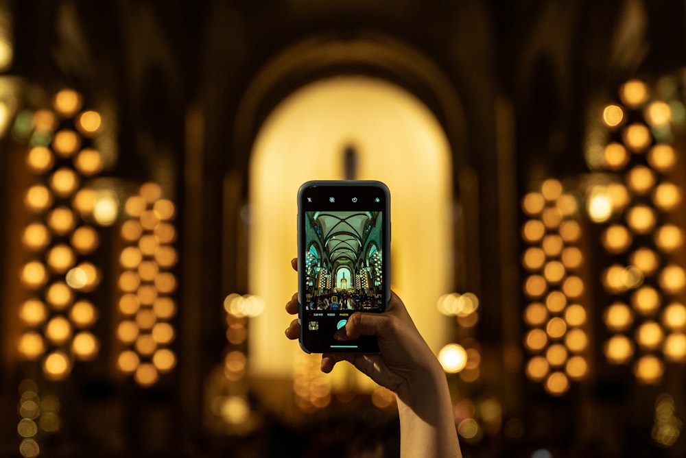 person holding black smartphone taking photo of lighted building