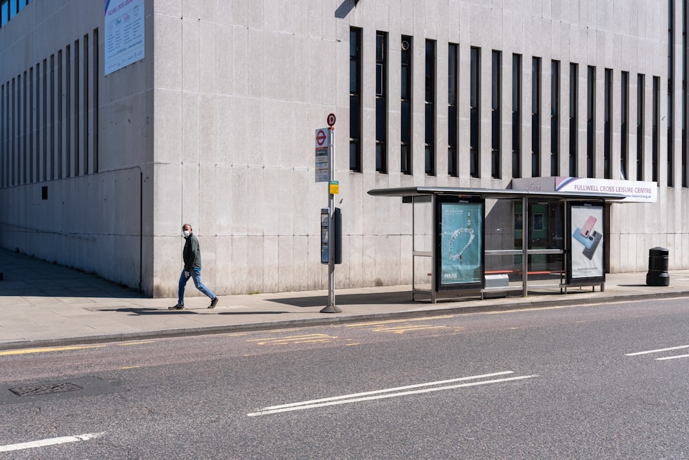 man in black jacket walking on sidewalk during daytime