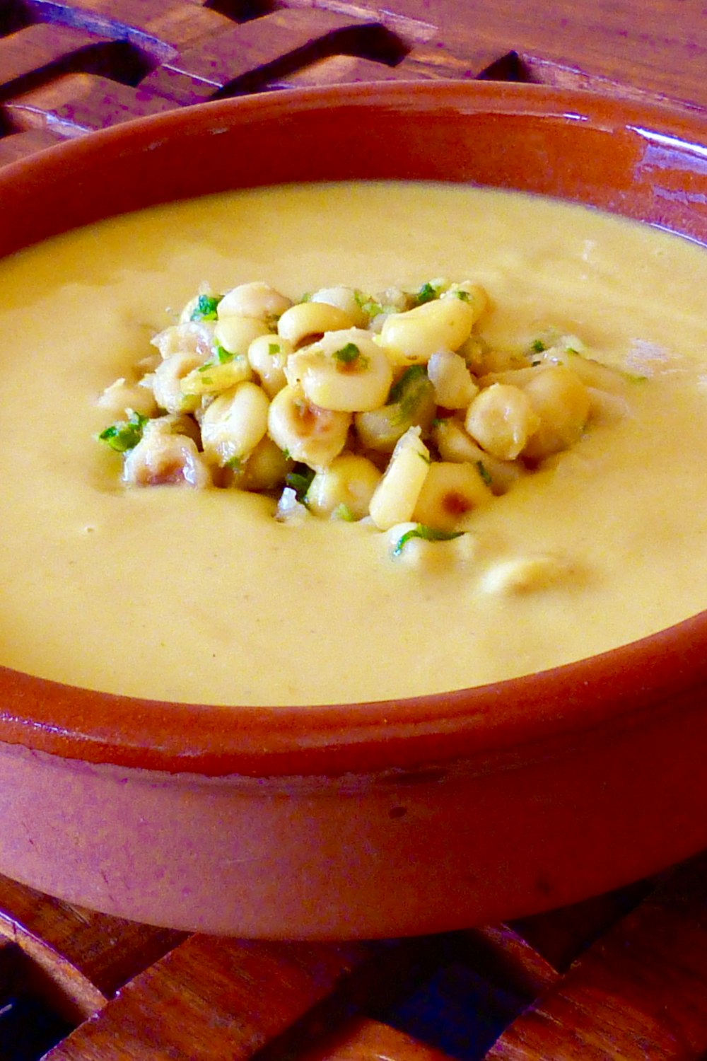 yellow soup with green vegetable in red ceramic bowl