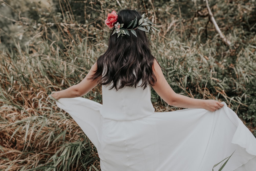 mujer en vestido blanco sosteniendo rosa roja