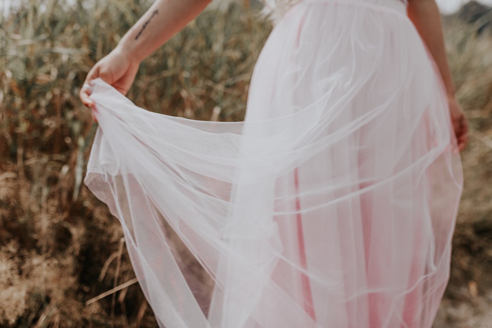 Mujer en vestido blanco de pie en el campo de hierba marrón durante el día