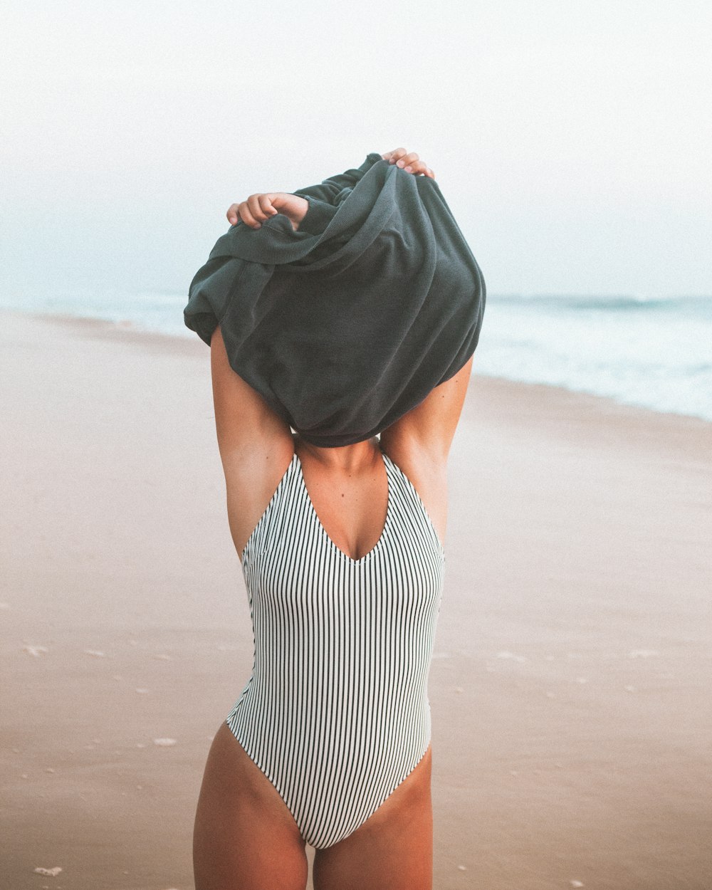 femme en robe rayée noire et blanche debout sur la plage