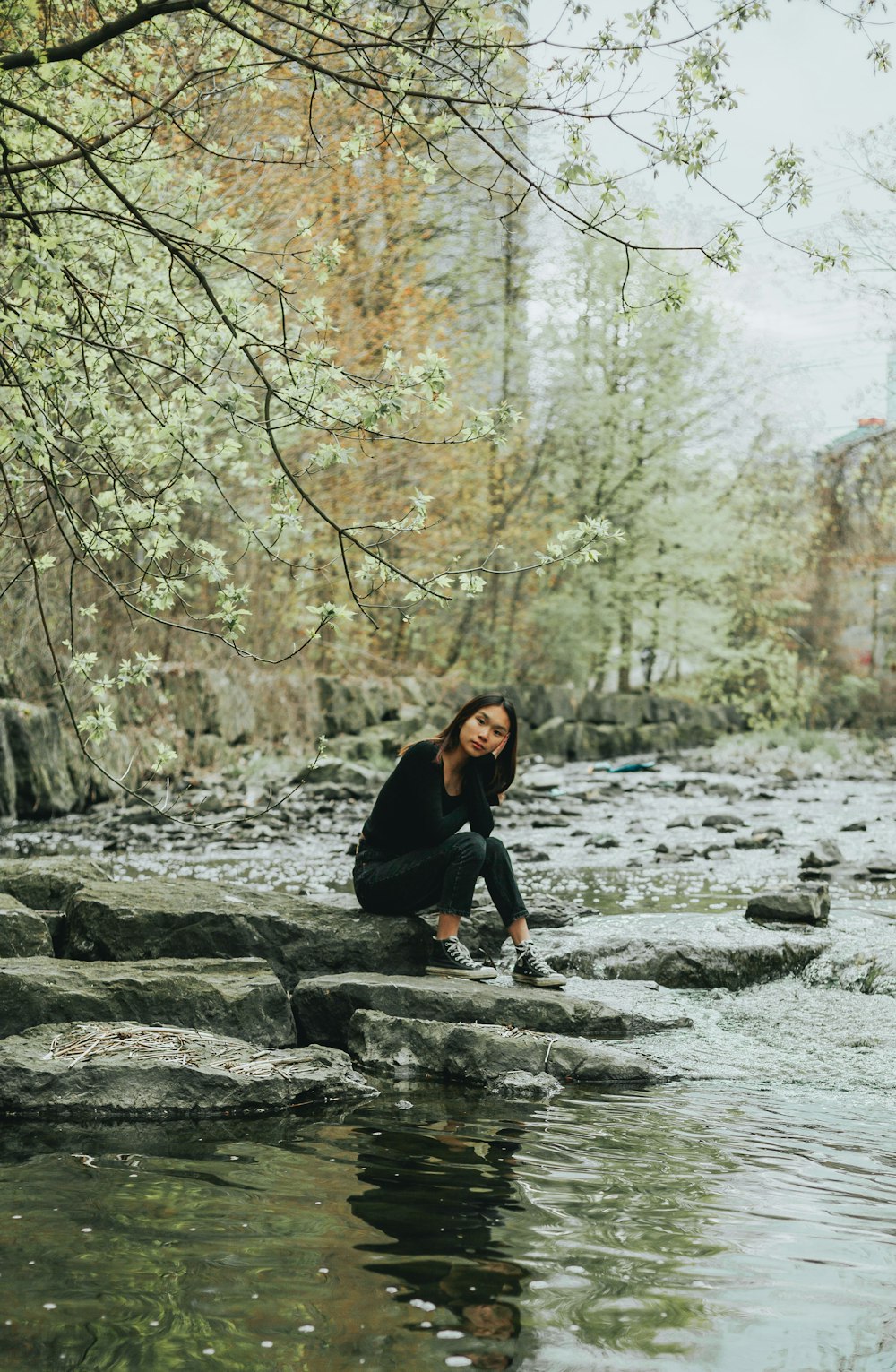 woman in black long sleeve shirt standing on rocky river during daytime