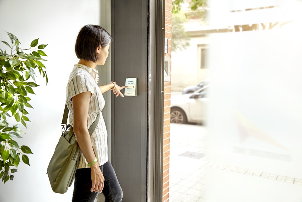 Femme en T-shirt gris et jean bleu assis sur une porte vitrée encadrée en bois blanc