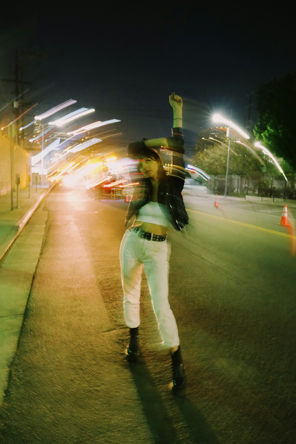 man in white pants and black backpack walking on street during night time