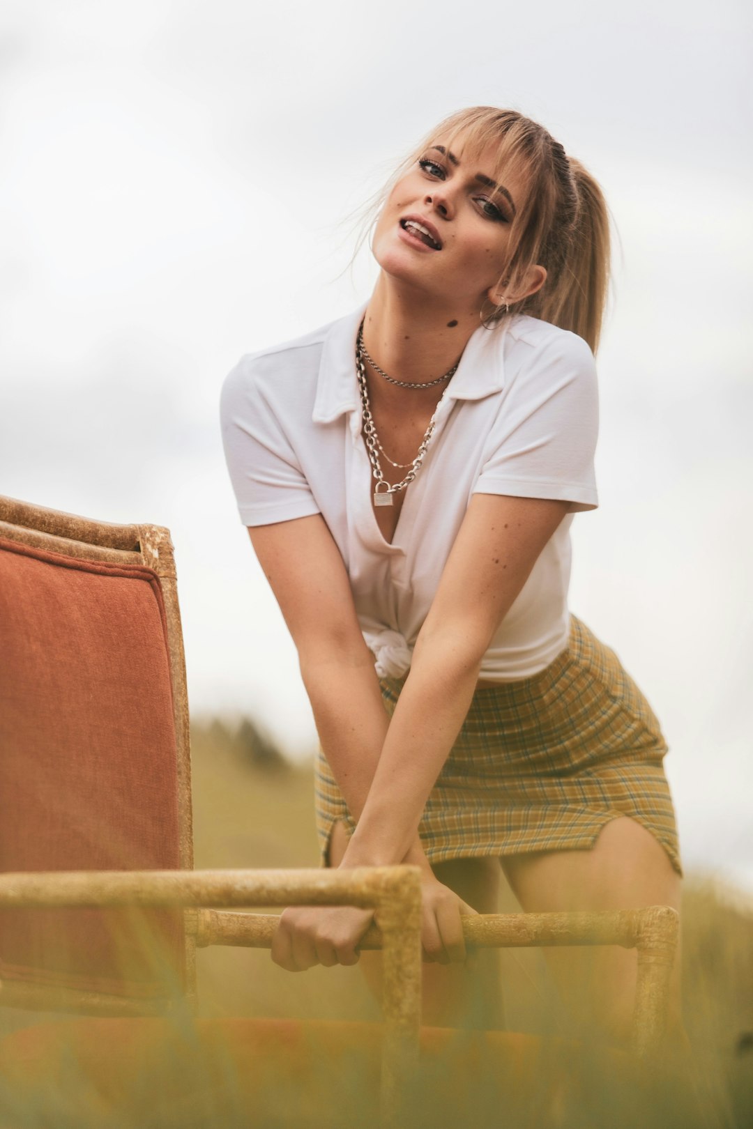 woman in white button up shirt and green skirt sitting on brown wooden bench during daytime