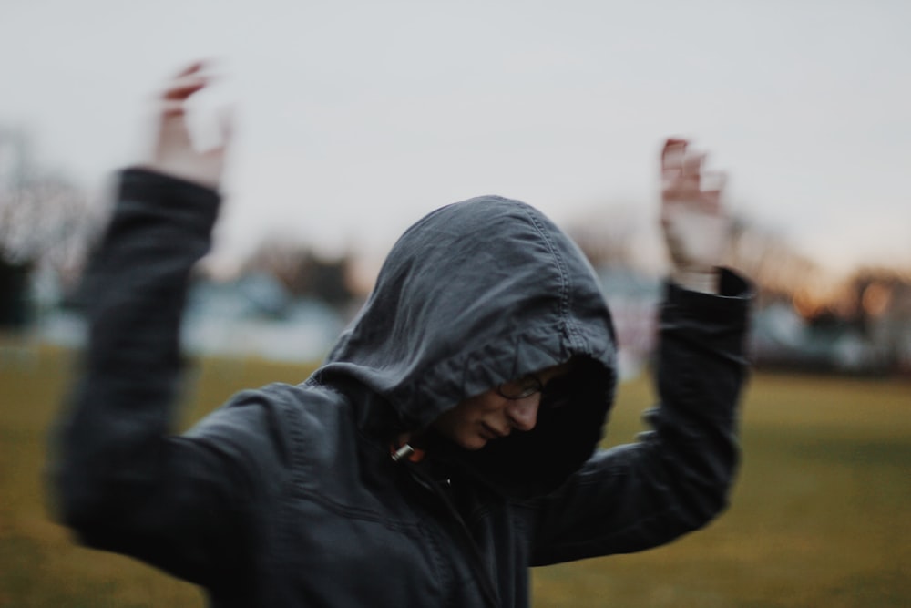 man in black hoodie raising his right hand