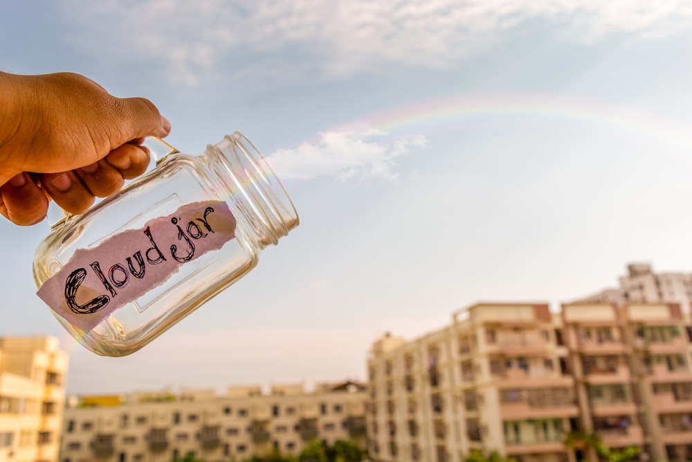 person holding clear glass bottle with water