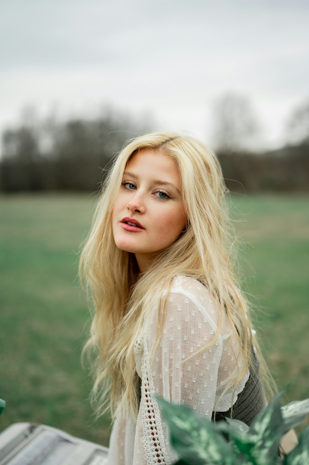 woman in white lace shirt standing on green grass field during daytime