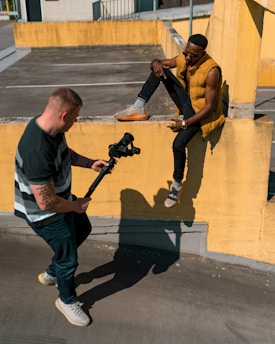 man in black and white crew neck t-shirt and blue denim jeans holding black dslr