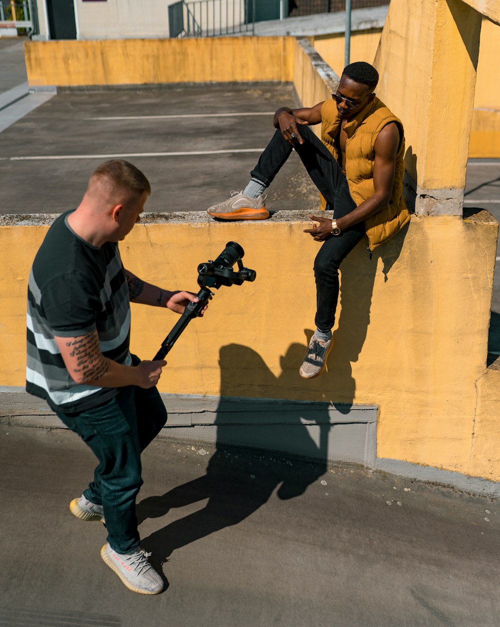 man in black and white crew neck t-shirt and blue denim jeans holding black dslr