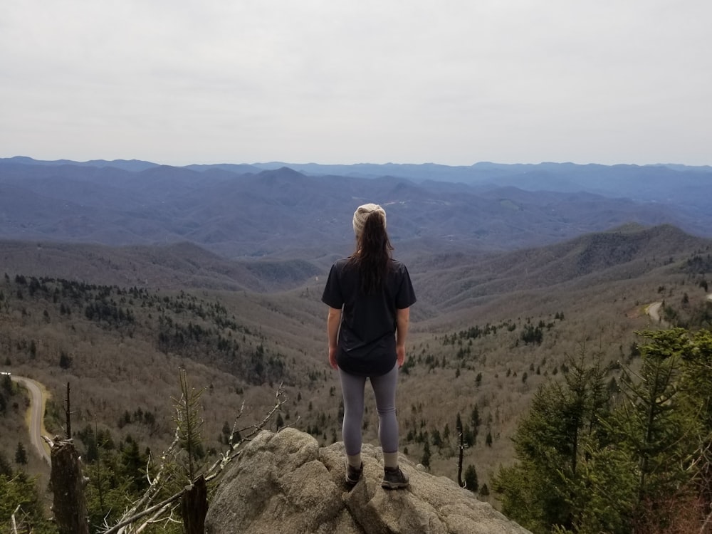 woman in black jacket standing on rock formation during daytime