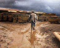 Workers inspecting mining equipment in protective gear amidst rugged coal mine terrain.