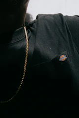 Close-up of a man wearing a black premium t-shirt with a subtle embroidered 'P' logo, highlighting fabric texture.