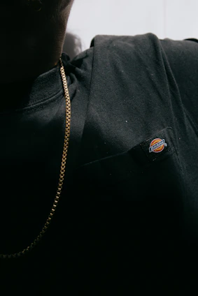 Close-up of a man wearing a black premium t-shirt with a subtle embroidered 'P' logo, highlighting fabric texture.