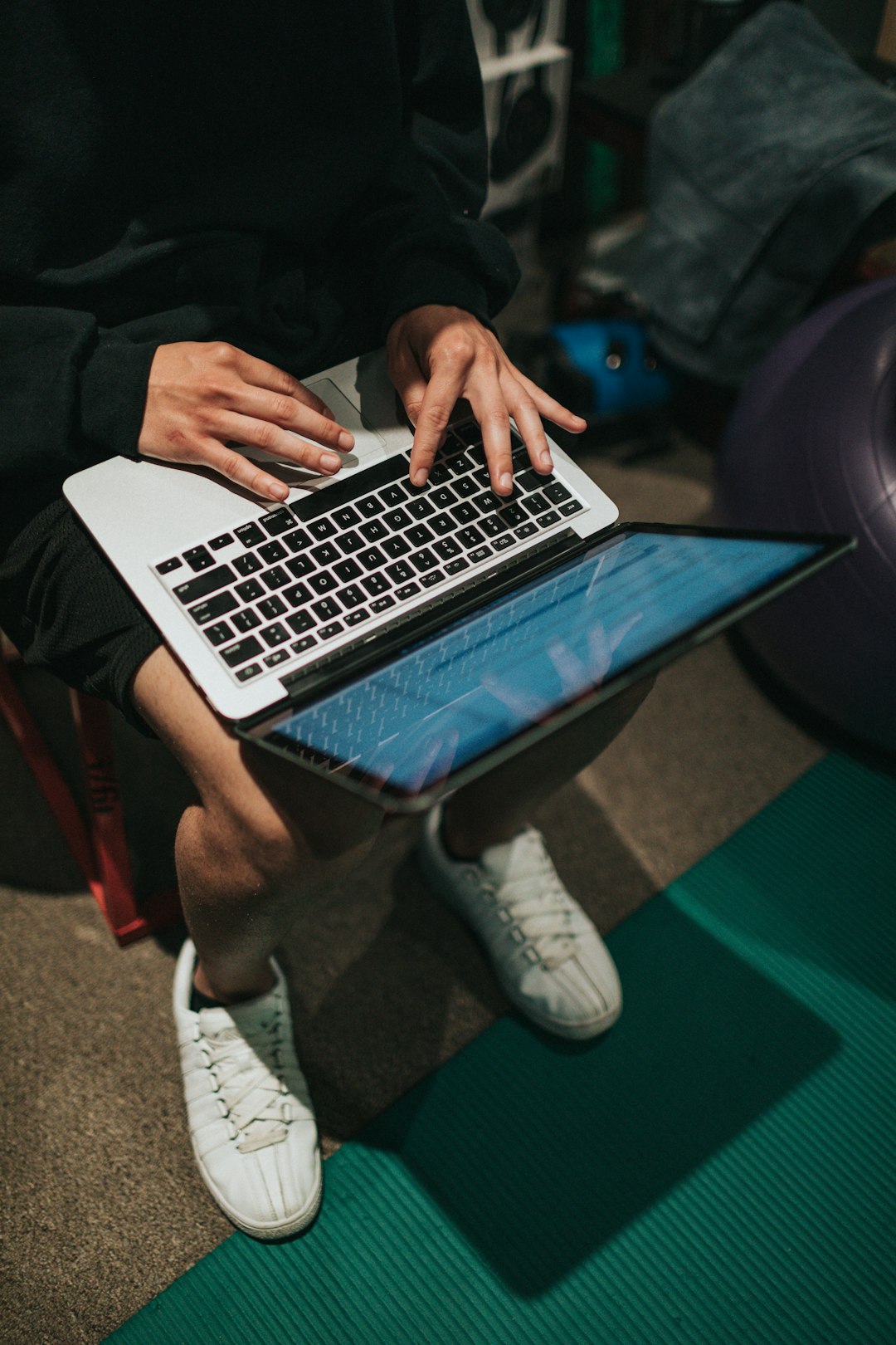 person in black pants and white socks using macbook pro