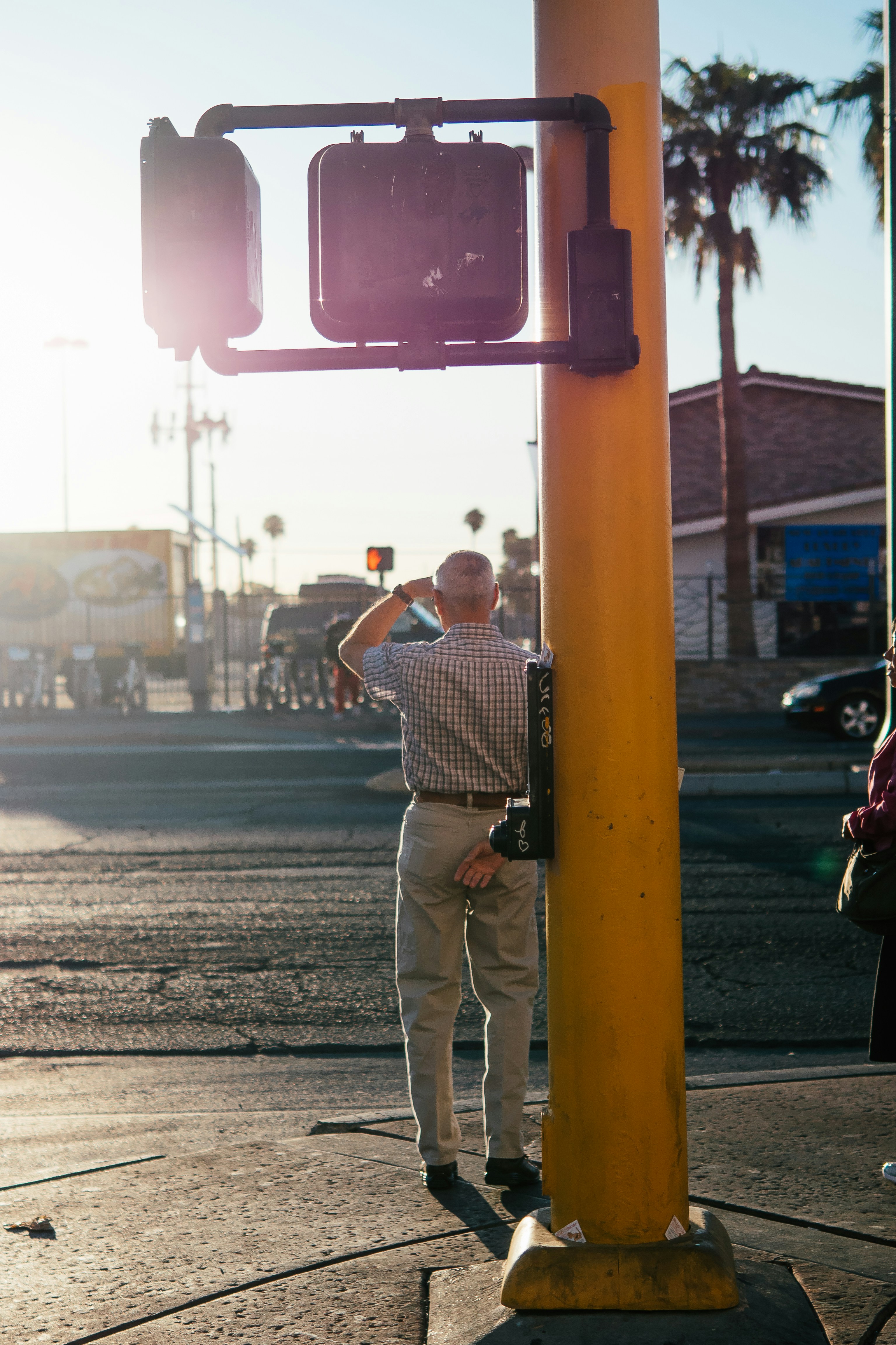 man in black and white stripe shirt and beige pants standing on sidewalk during daytime
