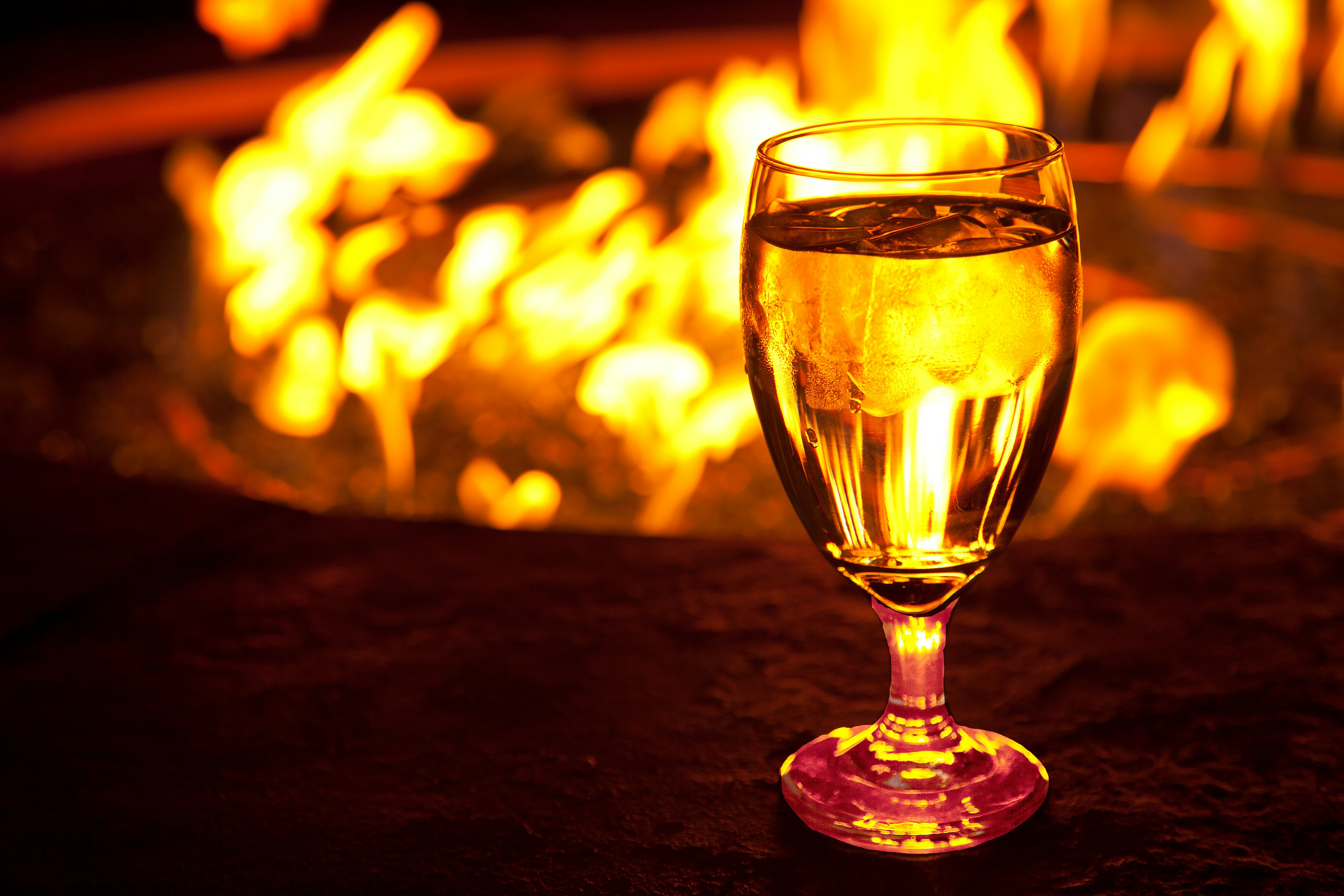 clear wine glass with yellow liquid on brown wooden table