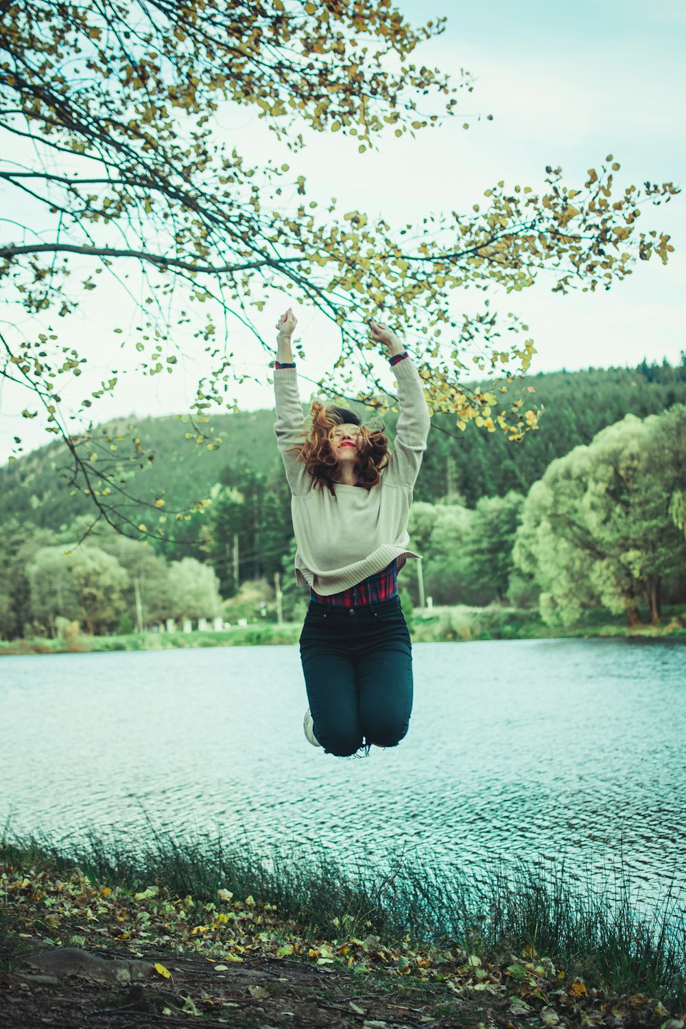 woman in white long sleeve shirt and blue denim jeans jumping on water during daytime