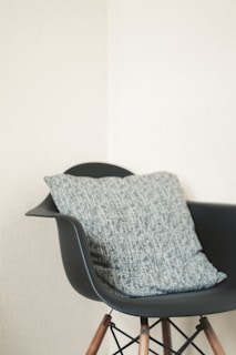 Front view of a sleek modern chair with wooden legs and a soft gray cushion