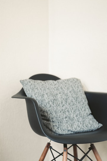 Front view of a sleek modern chair with wooden legs and a soft gray cushion