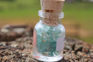 Small glass jar filled with smooth shilajit powder beside Himalayan stones.